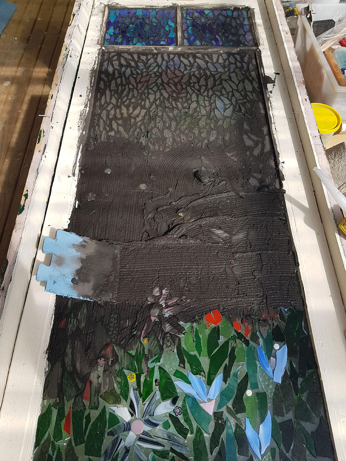 Grouting a glass mosaic on a secondhand window, Lisa Gill, Melbourne